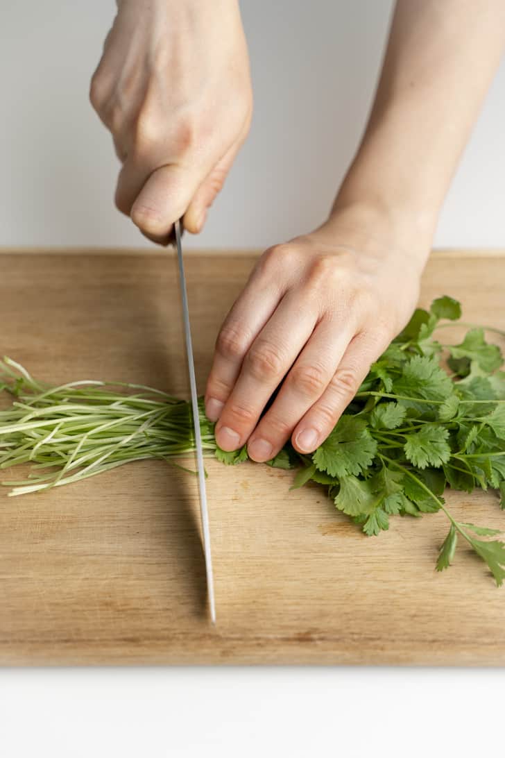 slicing the stems off one bunch of cilantro