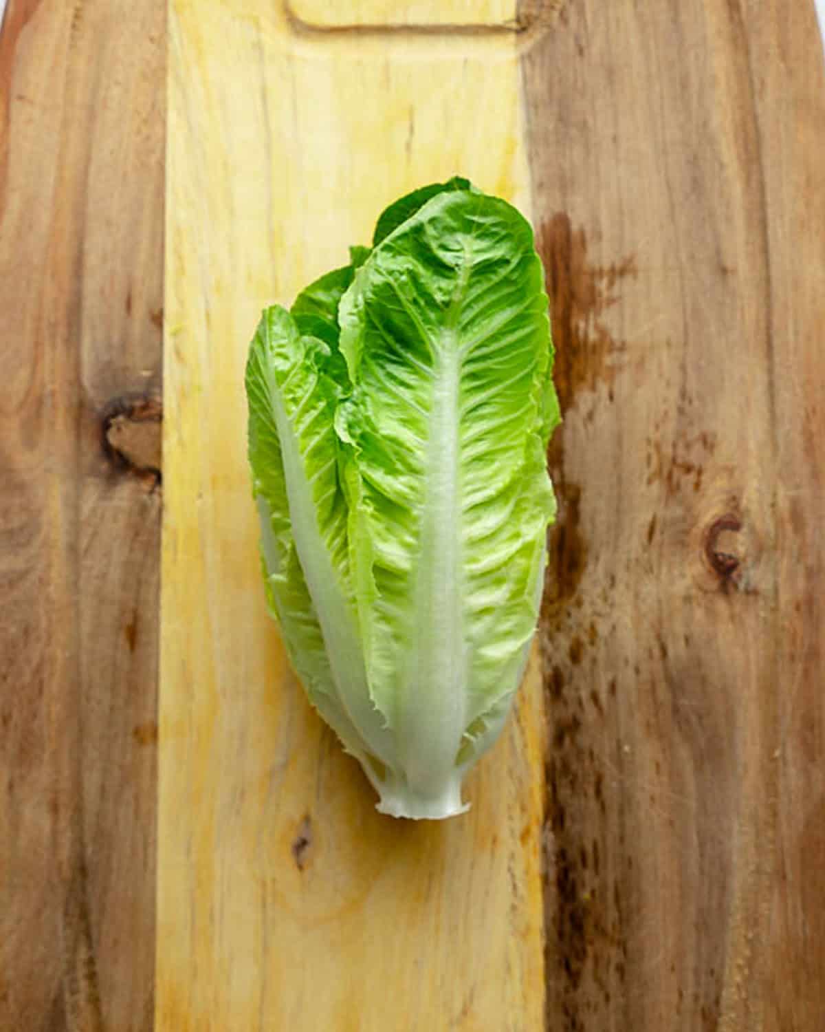 a whole romaine lettuce on a cutting board.
