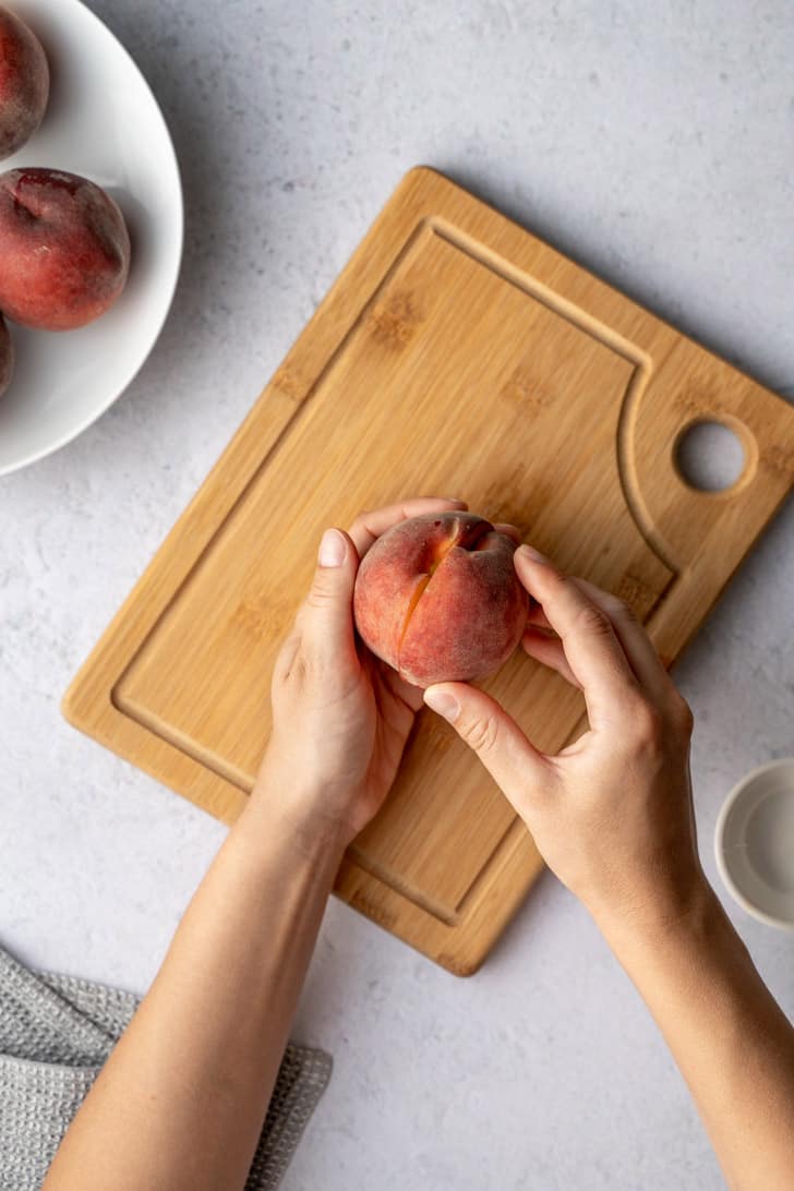pulling the peach apart with two hands