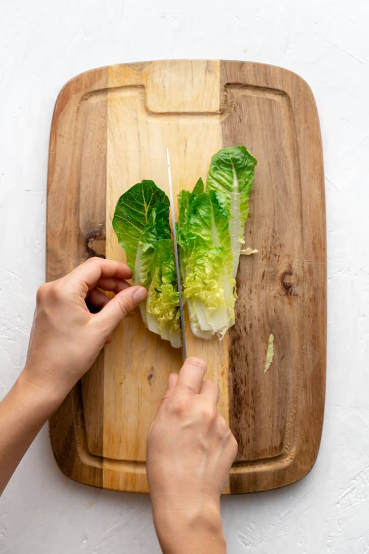 preparing romaine lettuce on cutting board with knife