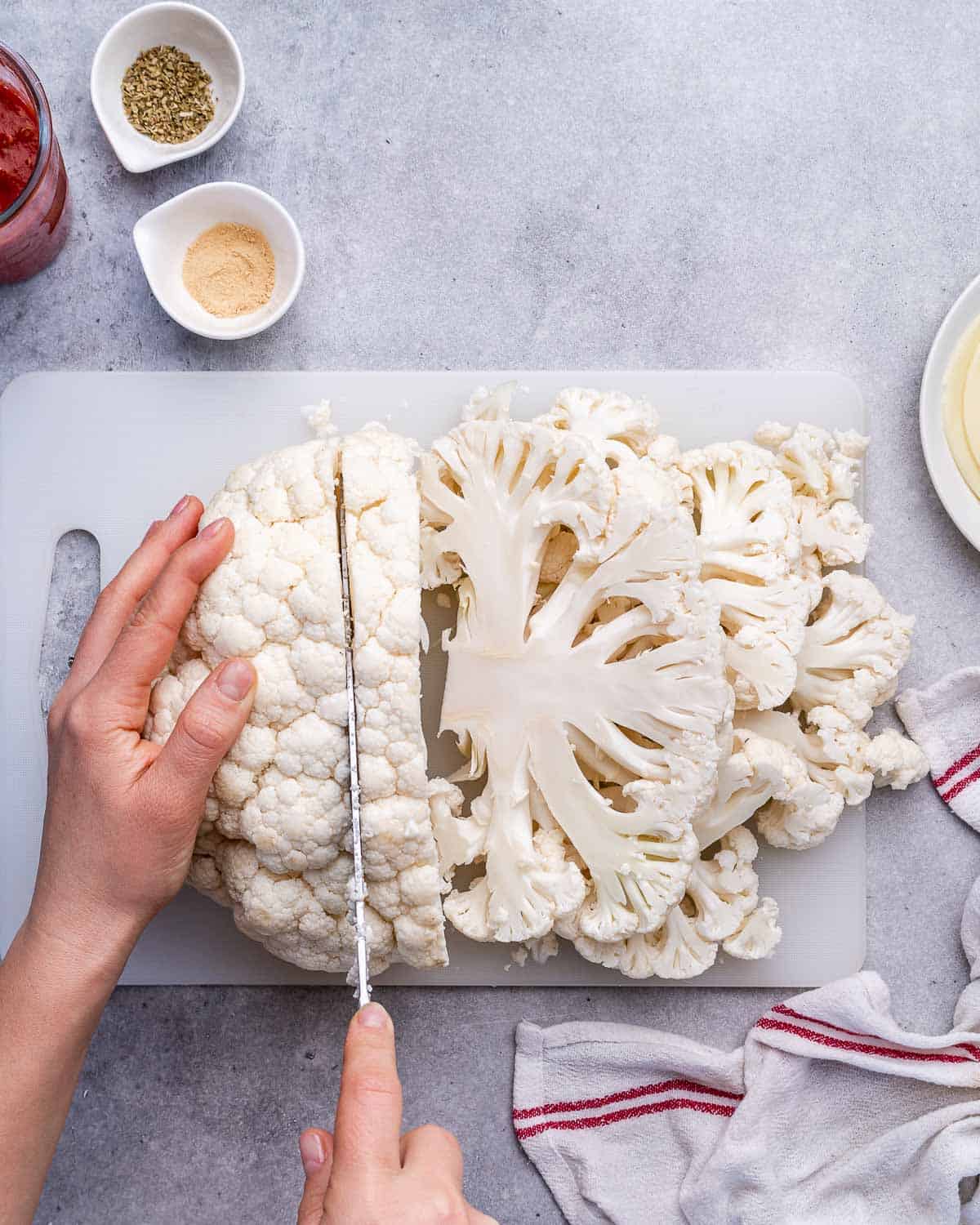 hand holding knife and slicing through a cauliflower