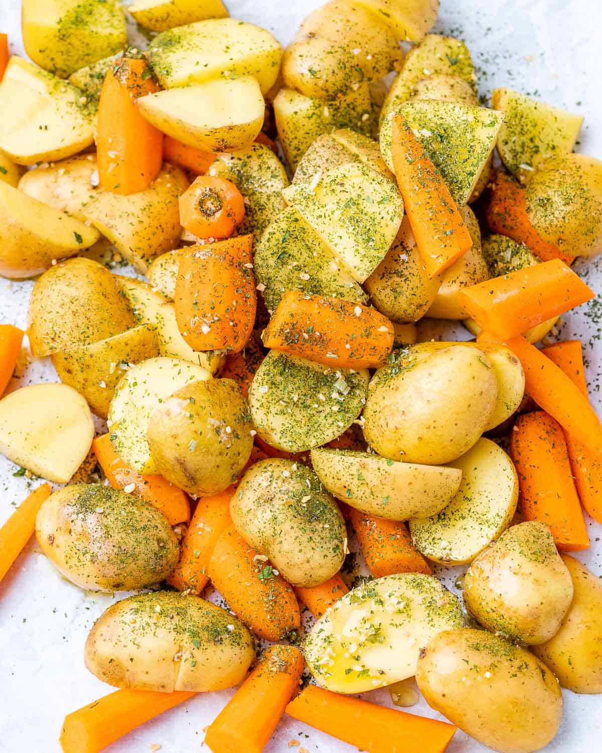 Tossing baby potatoes and carrots with seasoning.