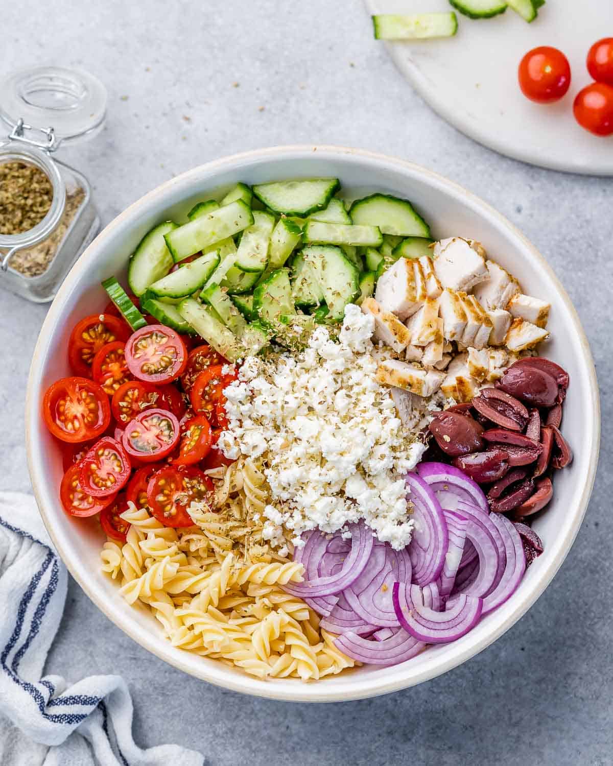 Greek salad ingredients in a large white serving bowl.