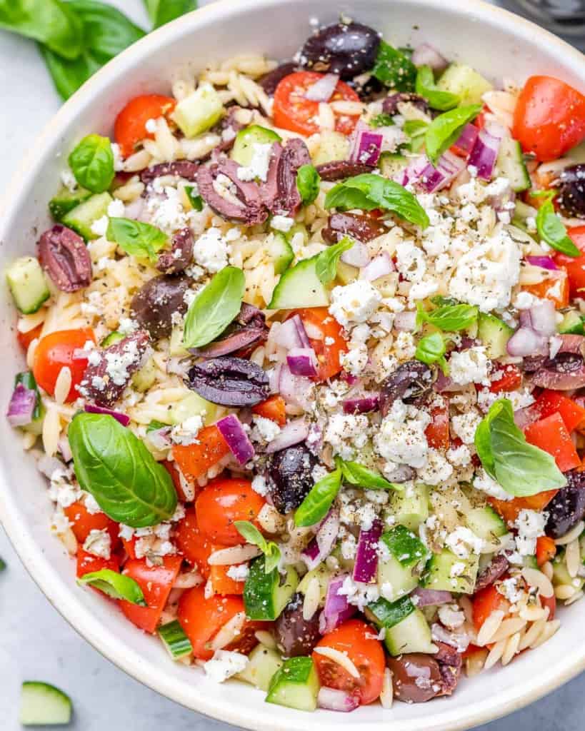 top view close up of greek orzo salad in a white round bowl