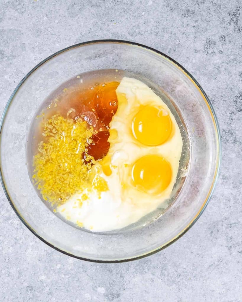 yogurt, egg, lemon juice and zest, oil, and honey in a clear round bowl before mixing 