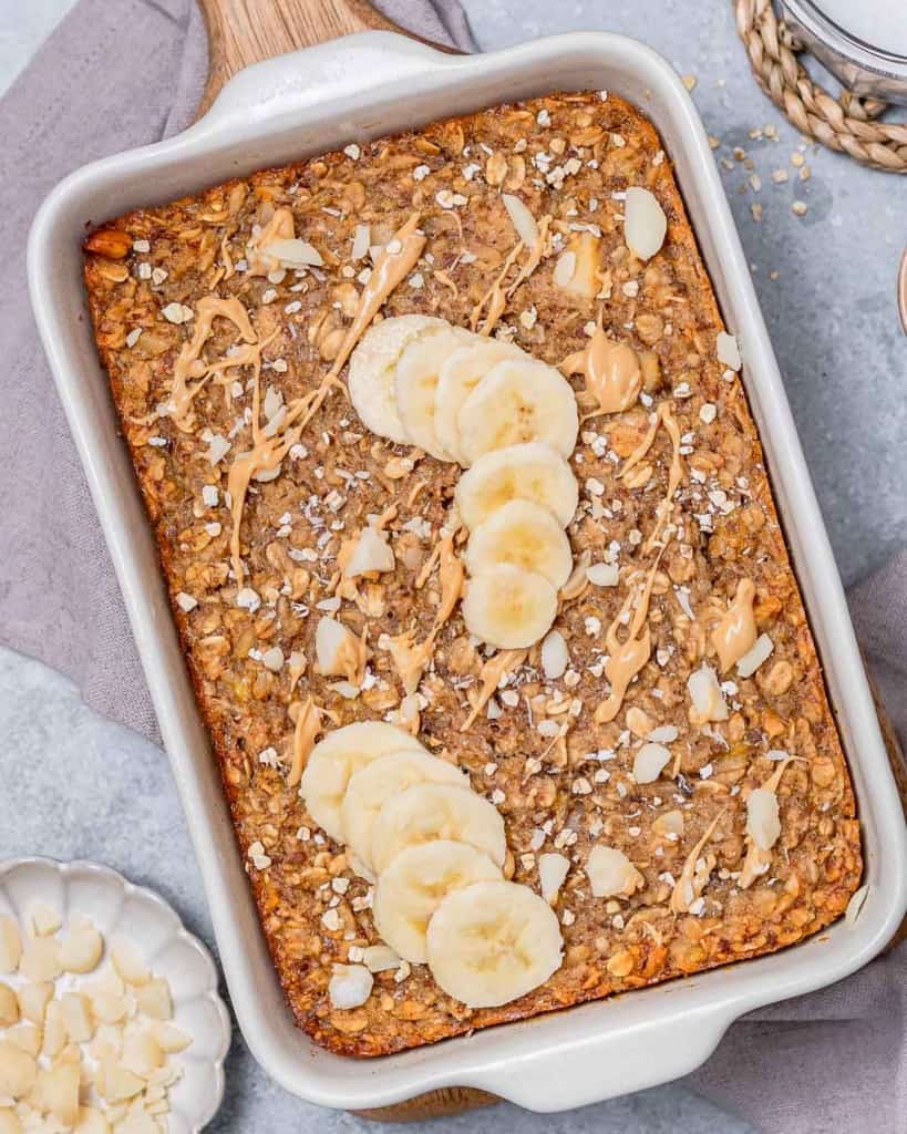 Baked oatmeal in a dish topped with peanut butter and bananas.