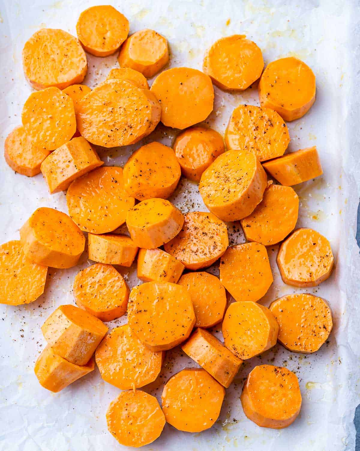 Sweet potato rounds on a parchment lined cookie sheet.