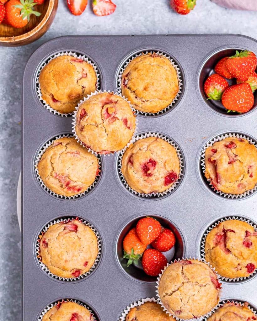 Muffins made with strawberries in a muffin pan.
