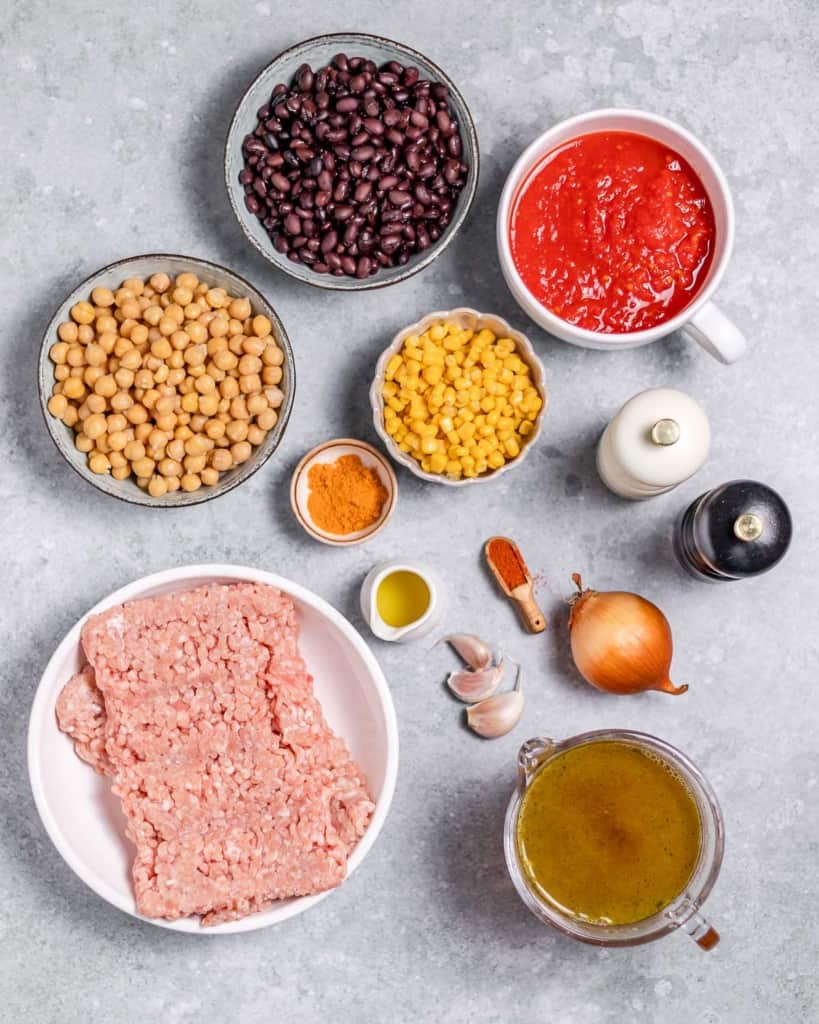 Raw ground turkey, beans and tomatoes divided into small bowls.