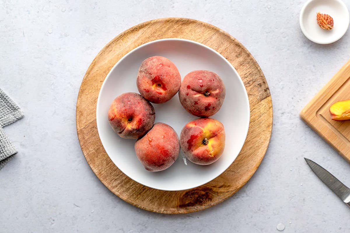5 peaches on a round plate.