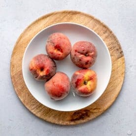 5 peaches on a round plate.