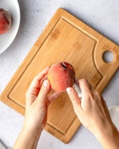 cutting a peach in half with a knife