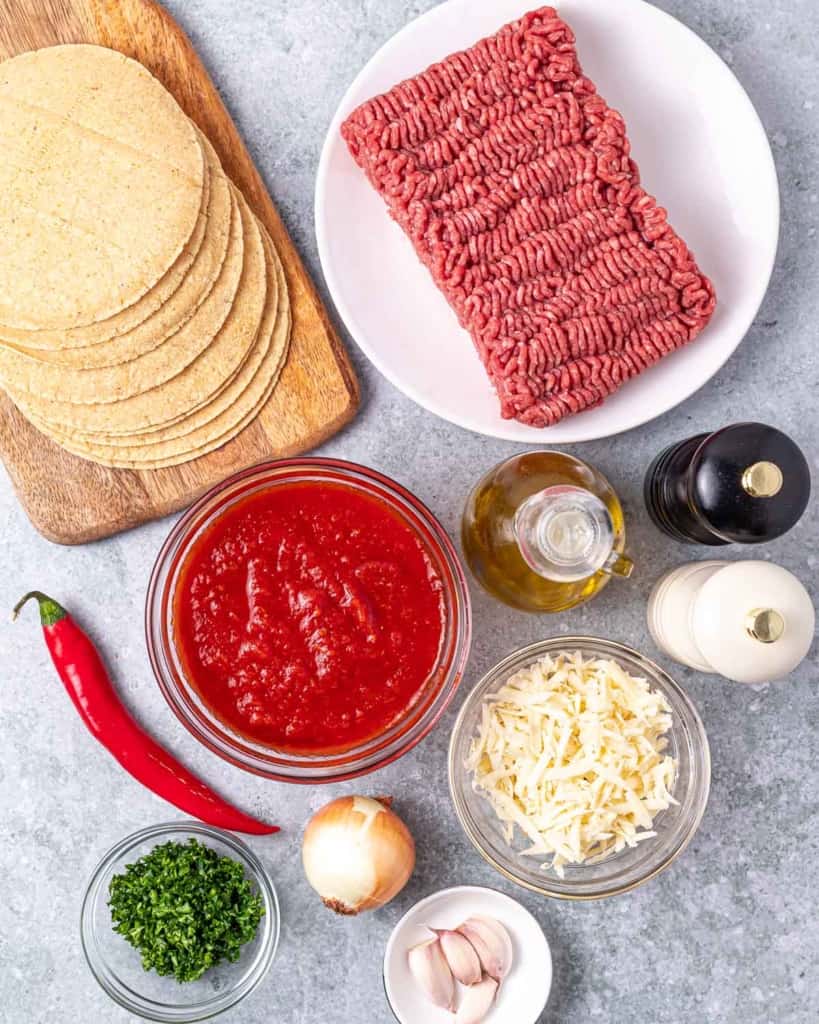Ingredients for making beef enchiladas, divided into portions.