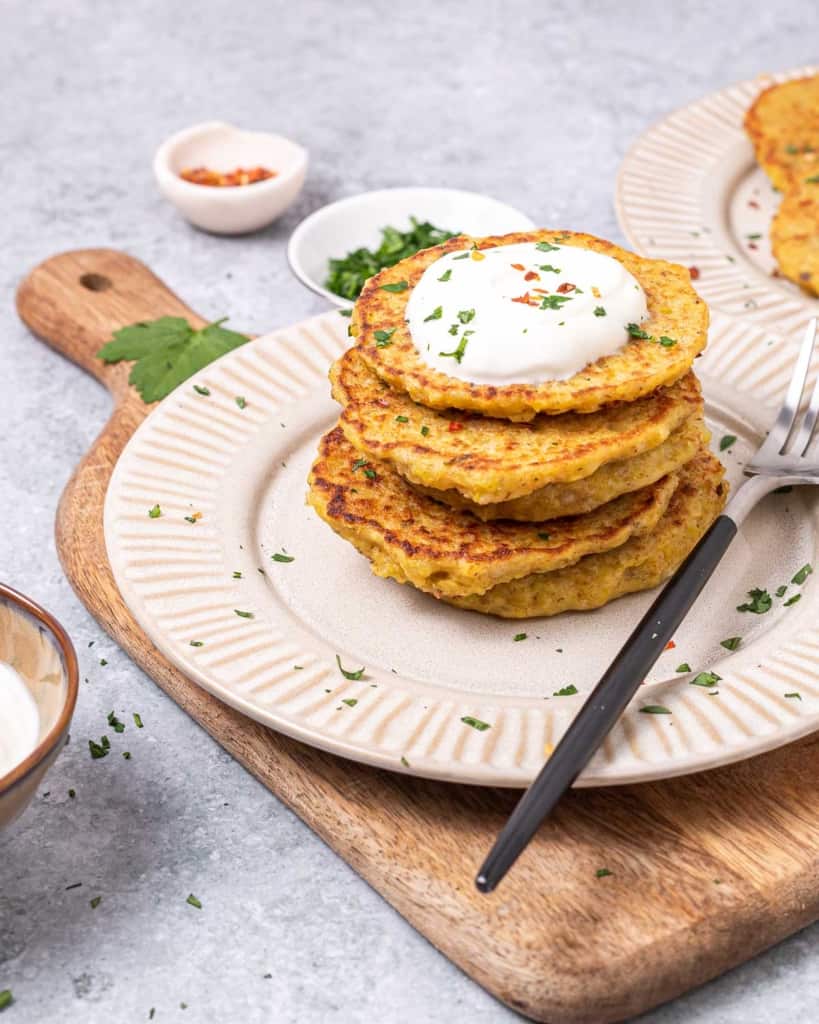 Potato pancakes stacked and topped with sour cream.