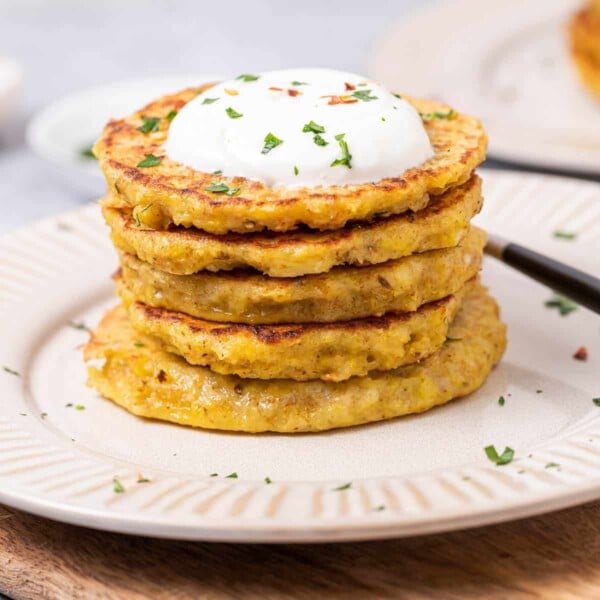 side shot of stacks of potato pancakes on a plate topped with yogurt