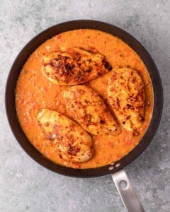 Simmering chicken in peri peri sauce in a pan.