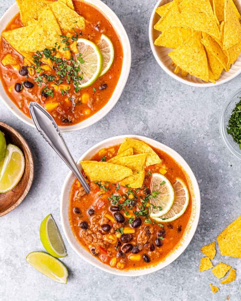 Bowls of beef enchilada soup served with tortilla chips.