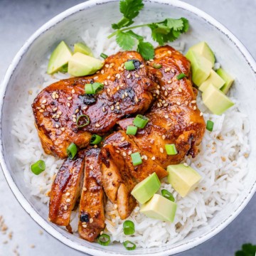 top view sliced korean chicken thighs over a plate of rice in a bowl