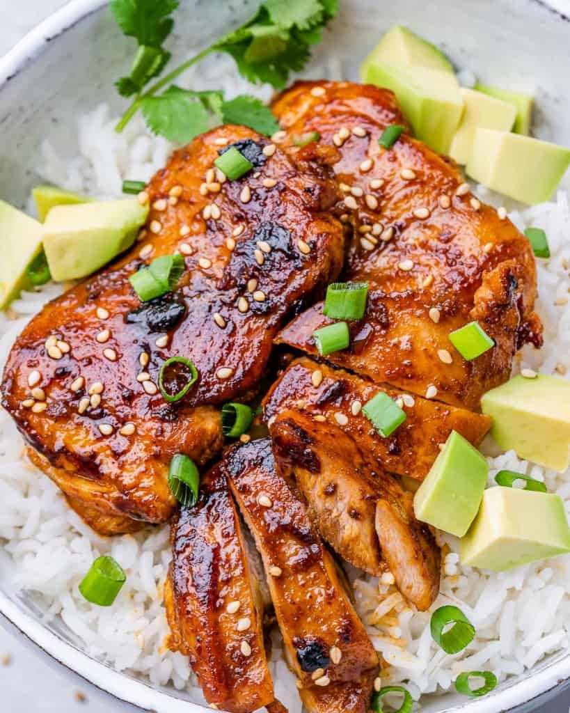 close up korean chicken thighs over a bowl of rice