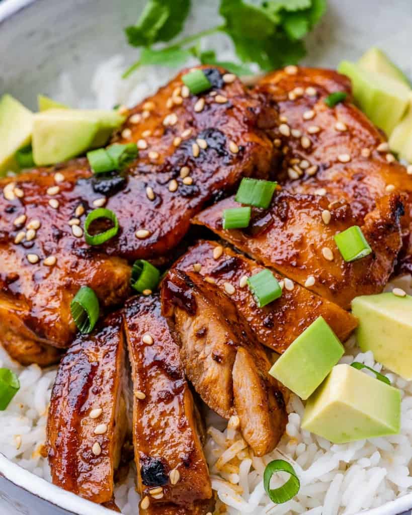 close up sliced chicken thighs over a bowl of rice