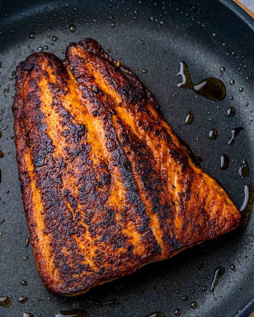 Searing salmon in a skillet.