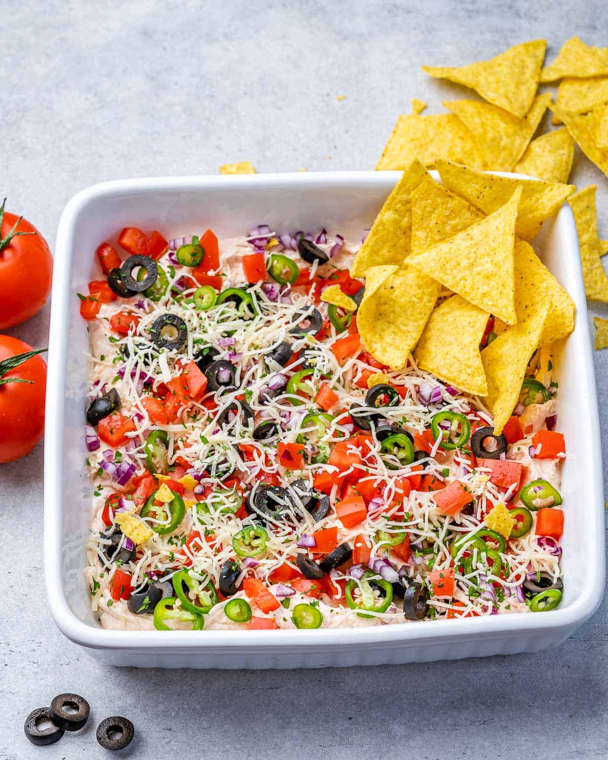 Taco dip topped with black olives, diced tomatoes, green onions and cheese.