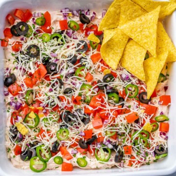 top view of taco dip in a dish with tortilla chips on the side
