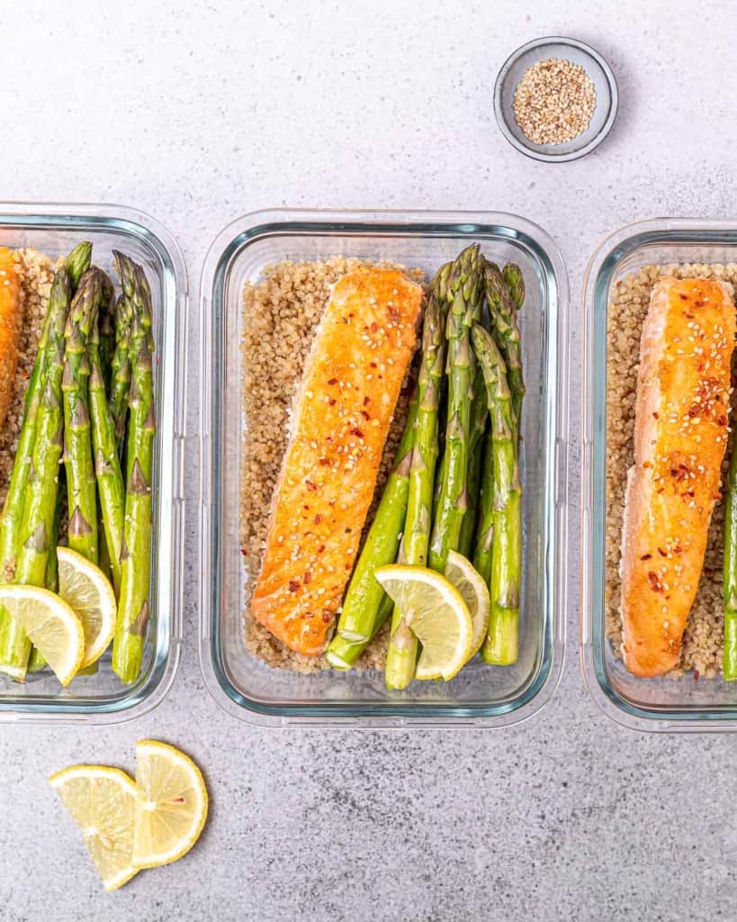 top view of 3 glass bowls with salmon asparagus and quinoa for meal prep