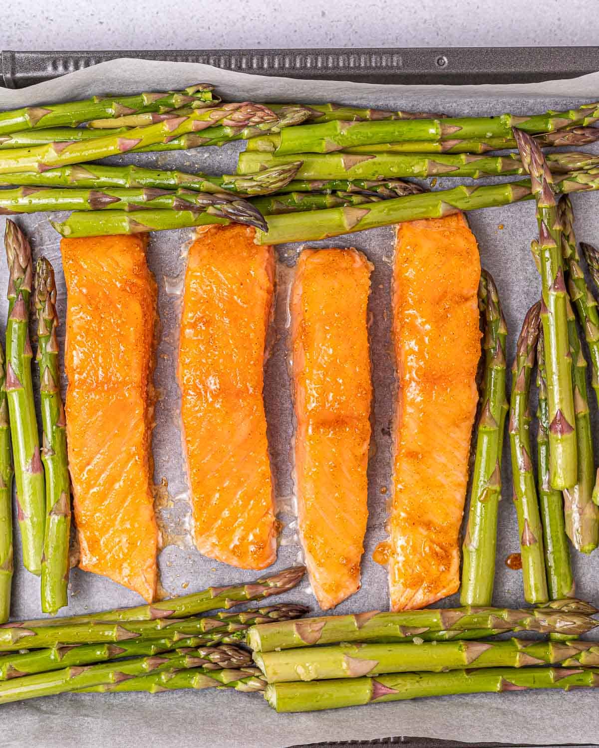 Placing salmon on a baking sheet with asparagus. 