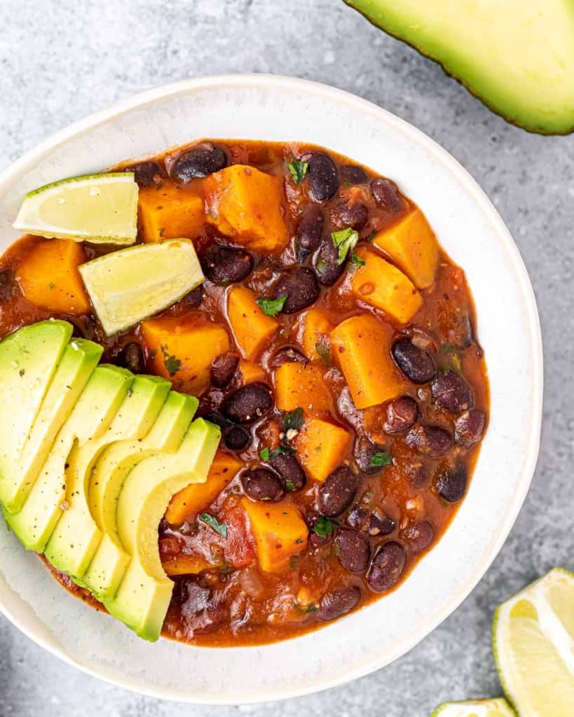 Stew made with sweet potato and black beans in a white bowl.