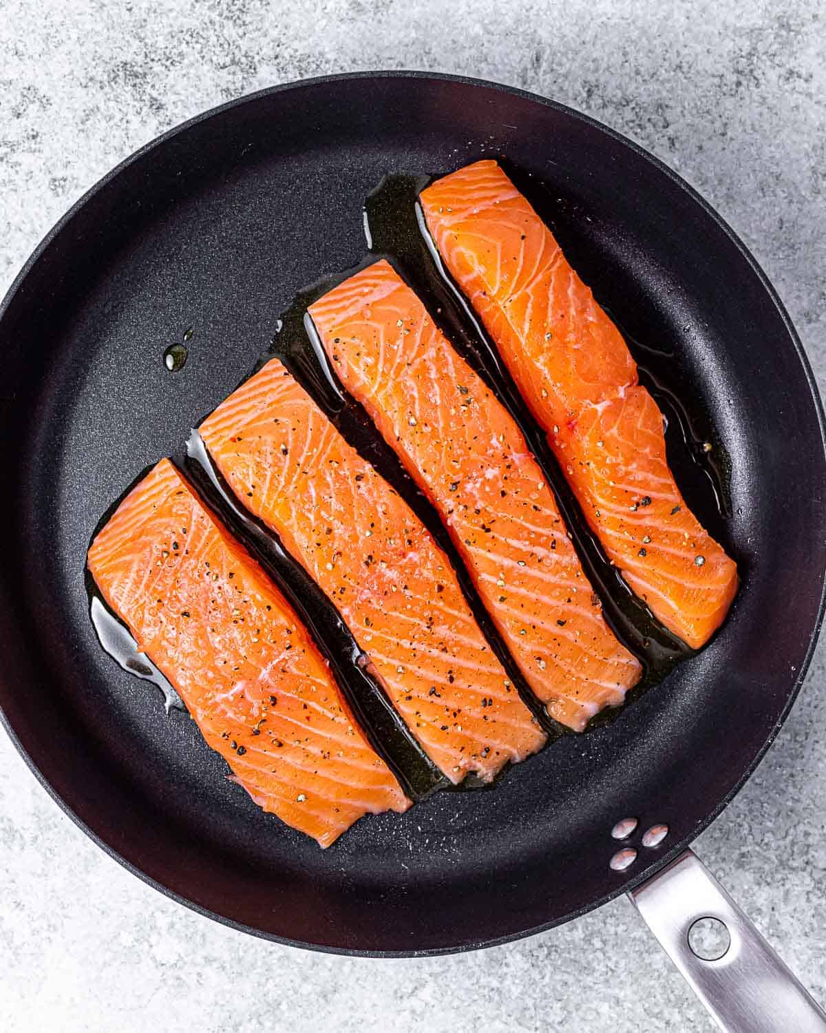 Salmon filets cooking in a large skillet.