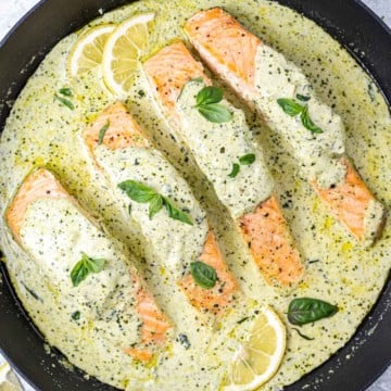 top view salmon in a creamy pesto sauce in a black skillet