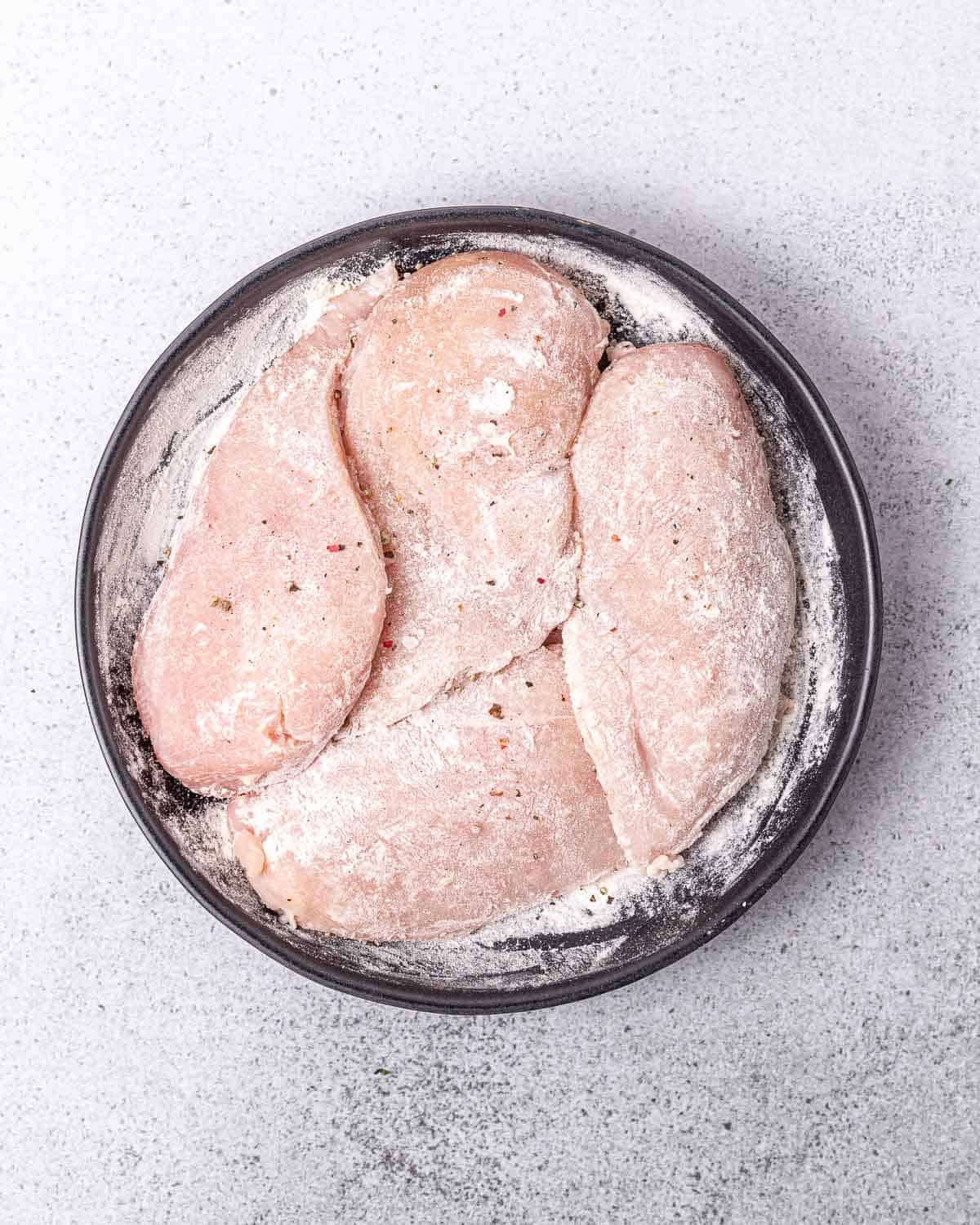 Coating chicken breasts in flour.