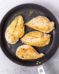 Searing chicken in a skillet.