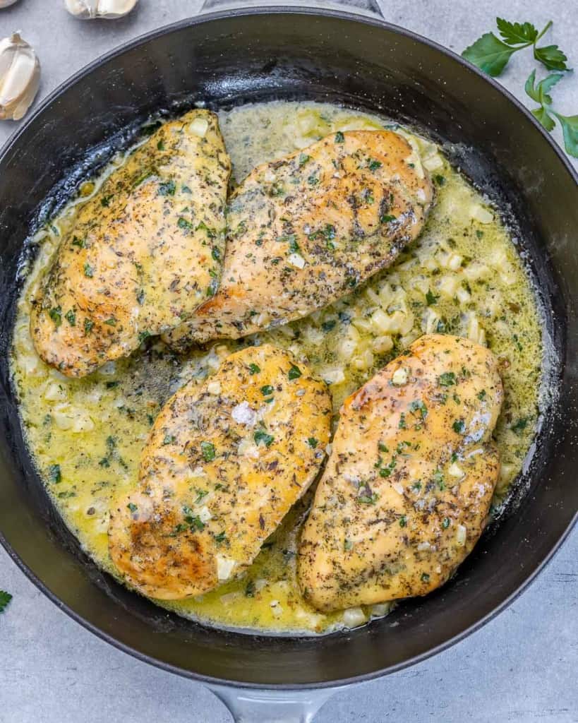 Chicken breasts cooking in a garlic butter sauce.