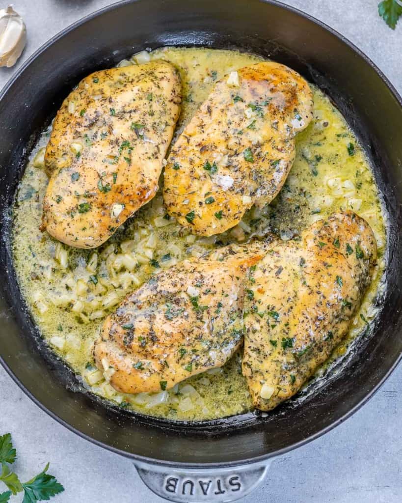 top view of black skillet with 4 chicken breasts in a garlic butter sauce 