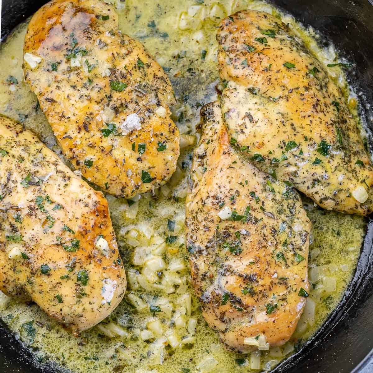 top view of chicken breasts in a garlic butter sauce in a round black skillet
