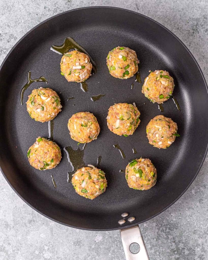 chicken meatballs on black pan before cooking