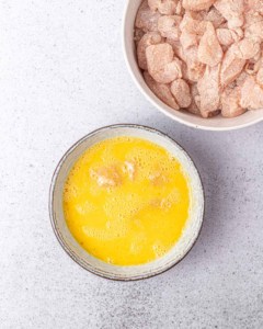 Dipping chicken in egg and olive oil mixture.