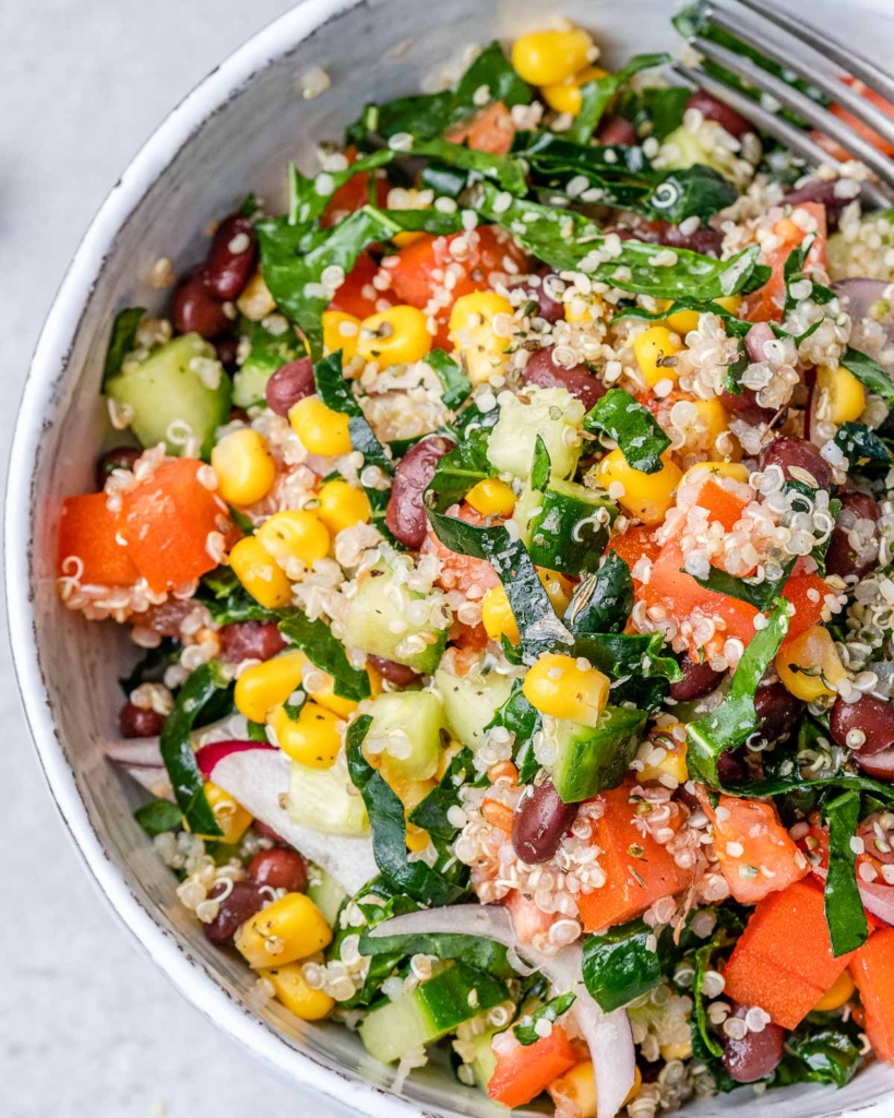Salad with tomatoes, corn and kale in a white bowl.