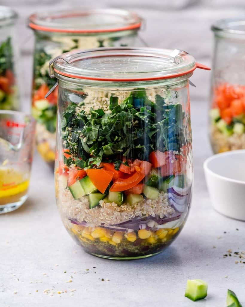 Quinoa, kale, tomatoes and cucumbers in a glass jar.
