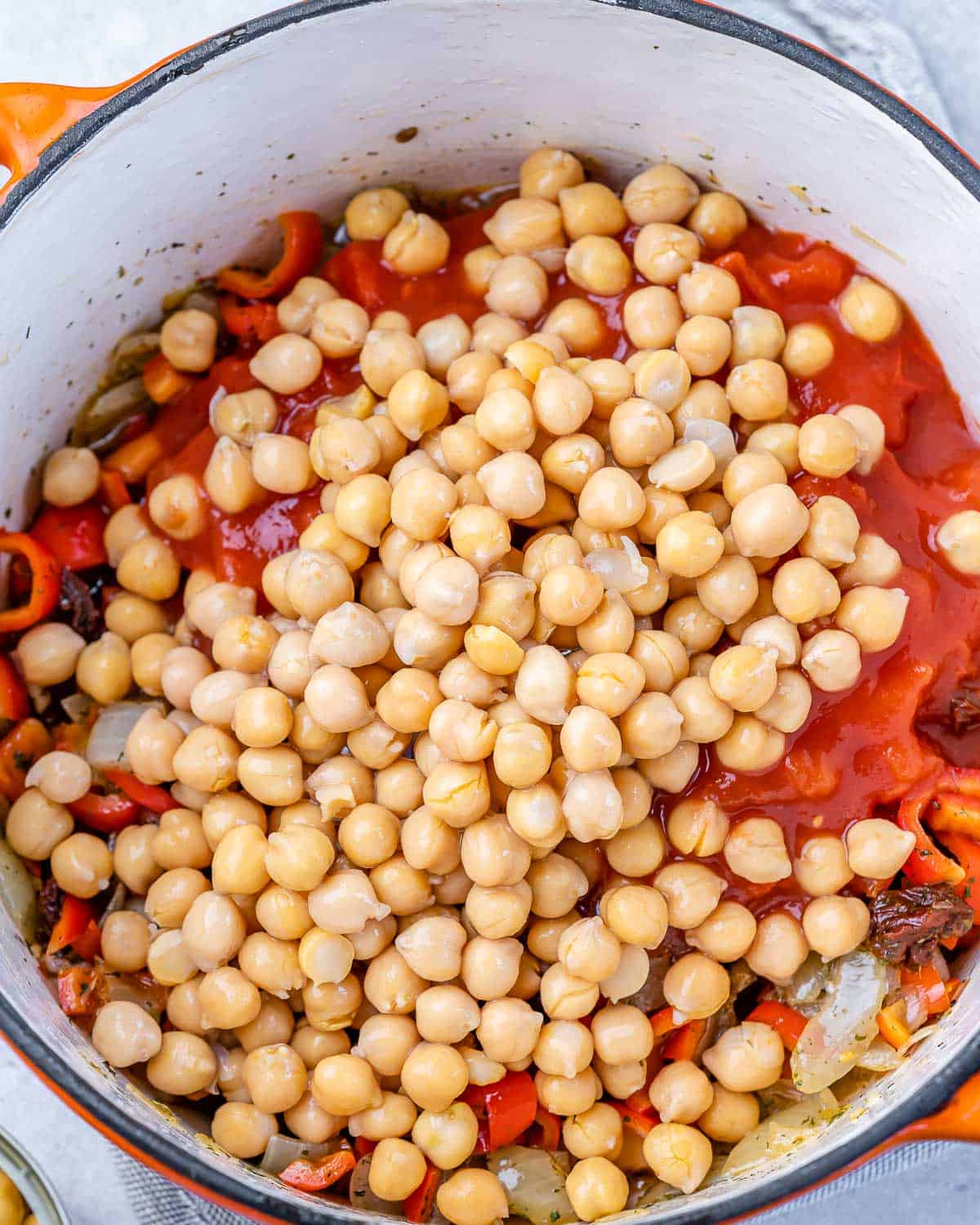 Adding chickpeas to stew in a large pot.