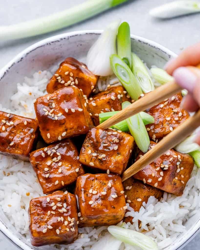 Using chopsticks to take a piece of tofu.