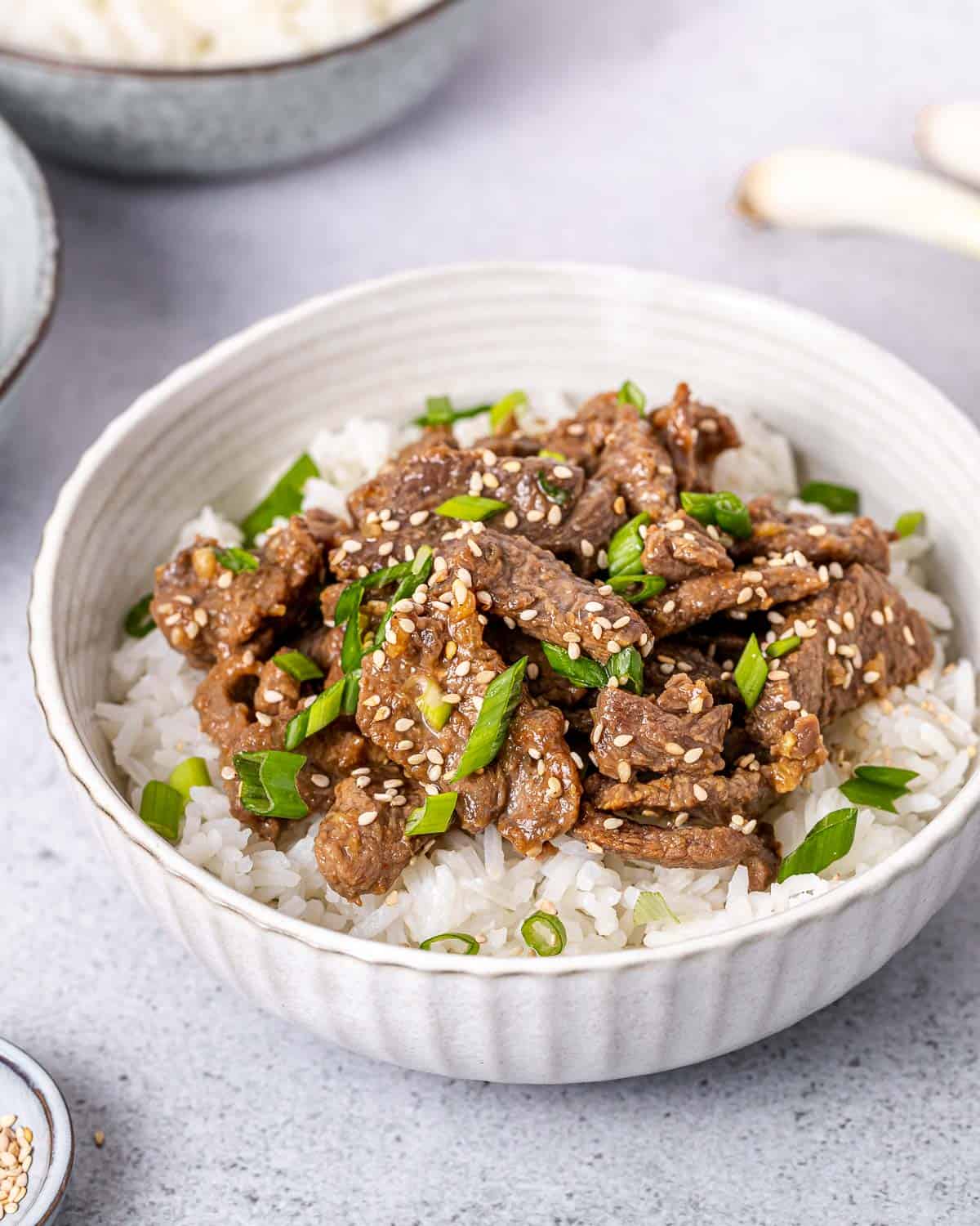 Serving Korean beef over rice in a white bowl.