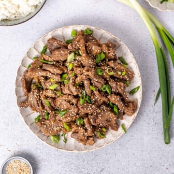 top view korean beef on a round white plate topped with sesame seeds