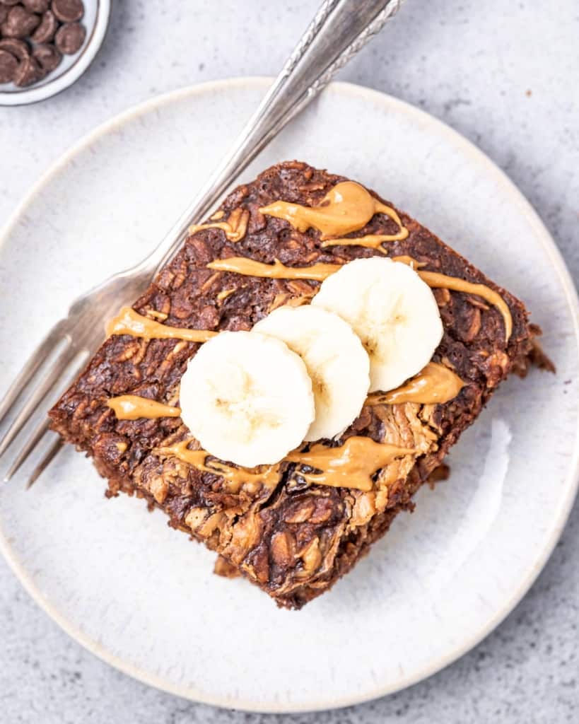 Slice of brownie baked oatmeal with banana slices served on a white plate.
