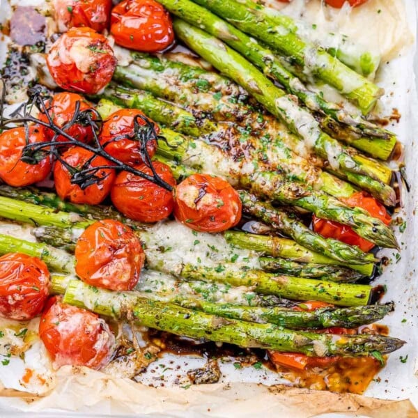 close up of baked asparagus with tomato and topped with parmesan