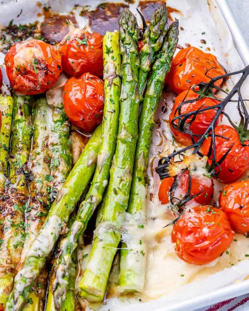 Balsamic asparagus served with cherry tomatoes on a white plate.