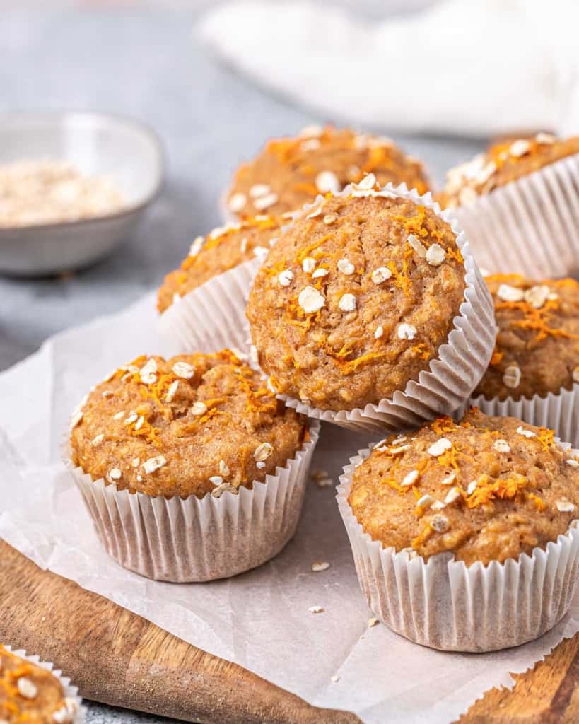 Carrot muffins stacked on parchment paper.