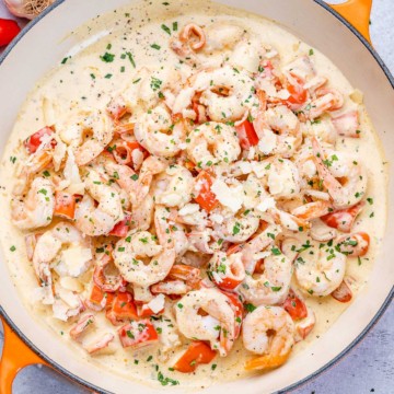 top view of sauteed shrimp in a creamy white sauce in an orange skillet